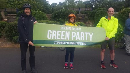Darren Parkinson; Hawarun Hussain; Martin Love holding a Bradford Green Party banner at Lister Park.