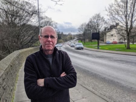 Councillor Martin Love stood next to Canal Road in Shipley with traffic in the background.