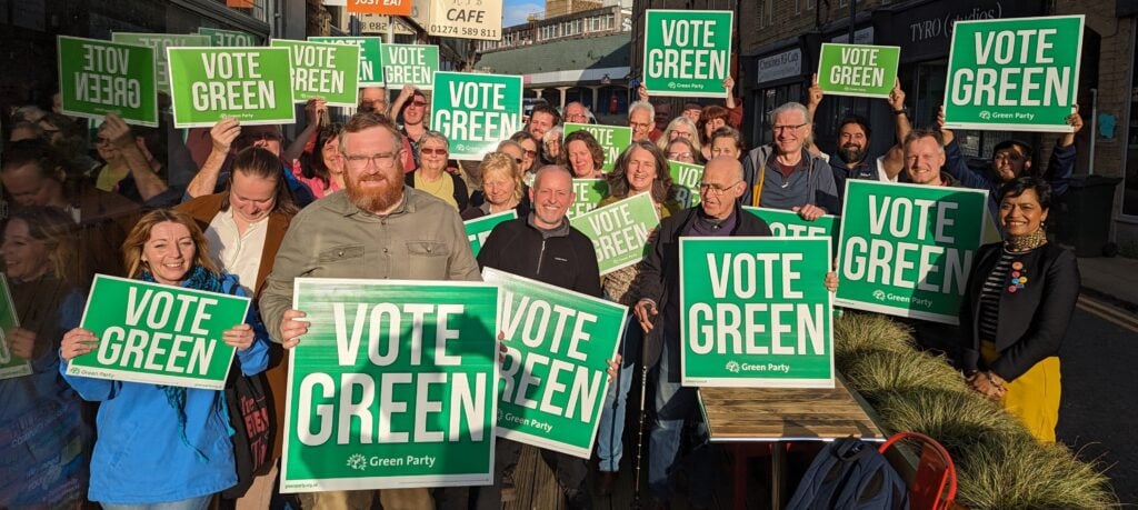 A group of Green Party volunteers holding "Vote Green" boards.